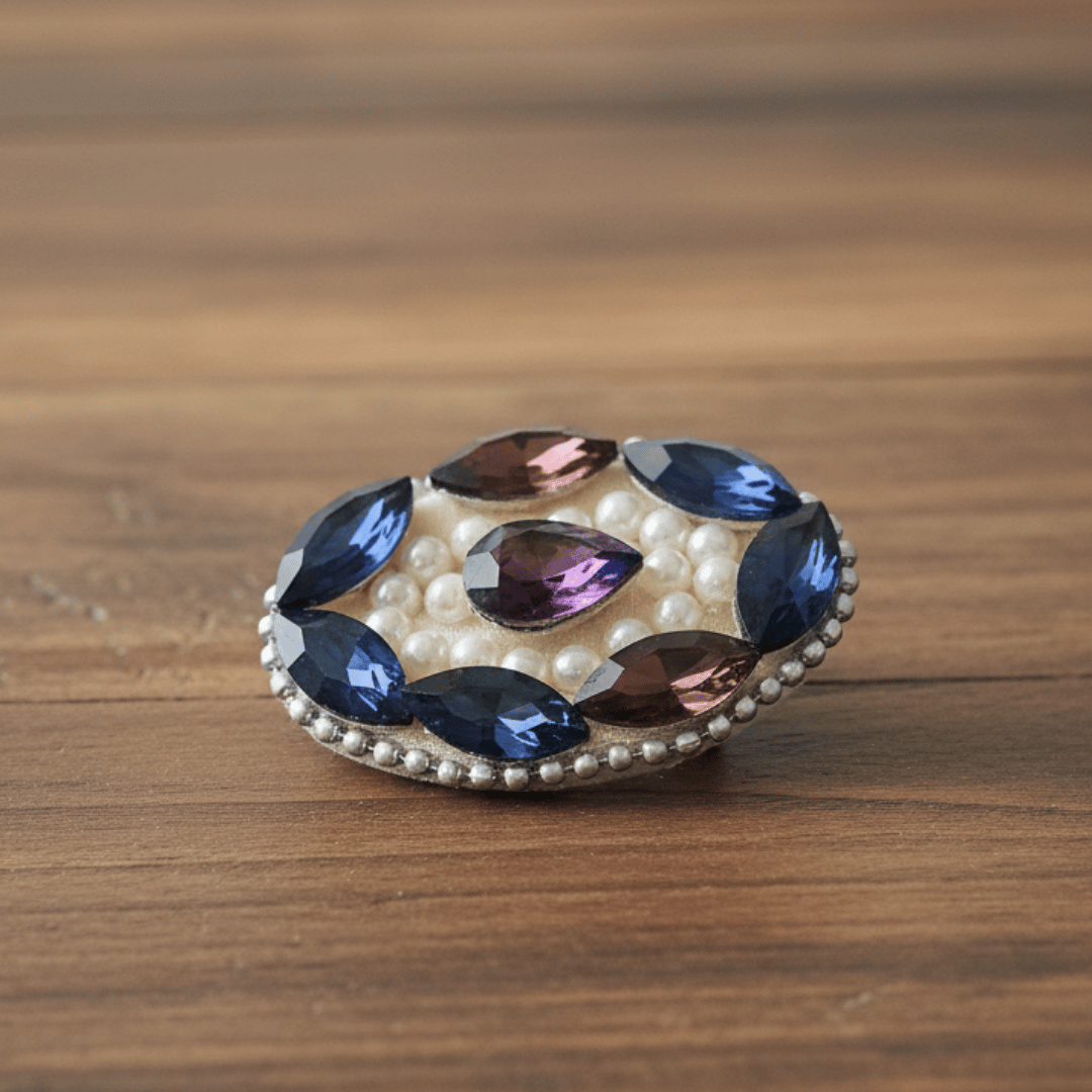 Wine Blue Crystal Pearl Saree Pin featuring sparkling crystals and pearls on a wooden background.