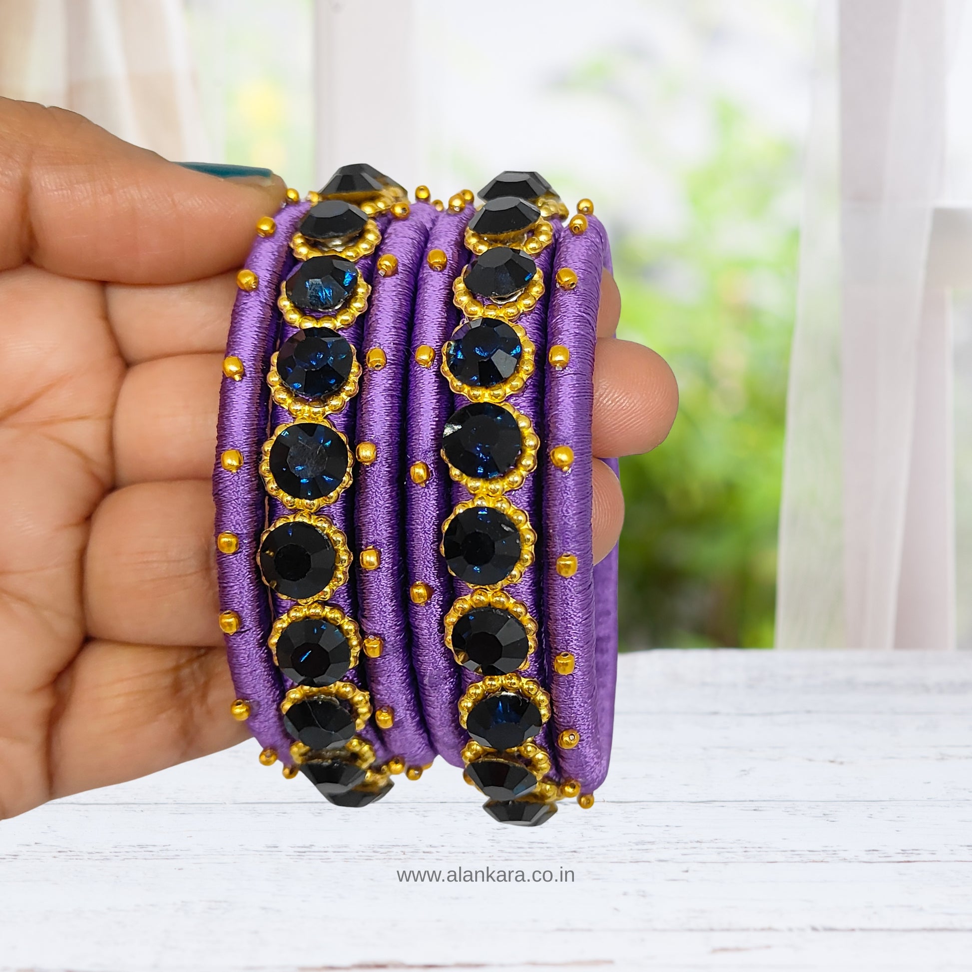 Royal Purple crystal Silk thread bangles featuring dark blue crystals and golden beads, showcased in a hand.