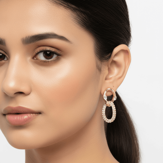 Close-up of a woman wearing gold plated cubic zirconia hoop earrings with a plain background