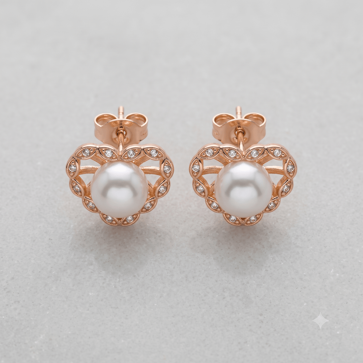 Pearl heart stud earrings with rose gold plating and cubic zirconia accents on a light background.