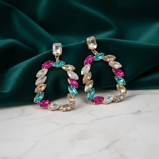 Colorful hoop earrings with gemstones on a green fabric background