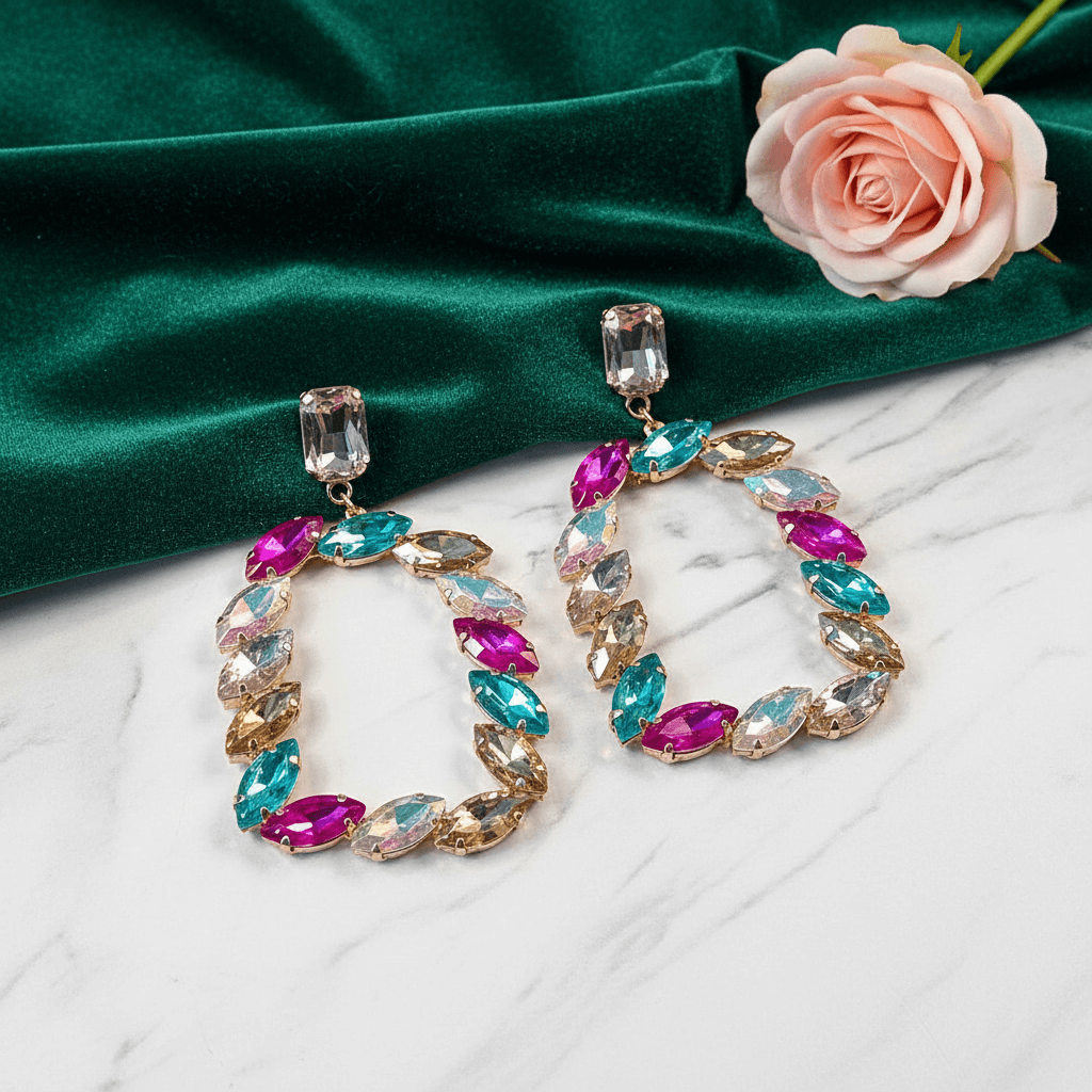 Multicolor stone hoop earrings on a green fabric background with a pink rose.