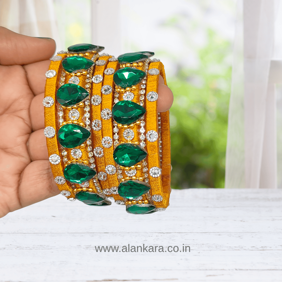 Golden Green Crystal Silk Thread Bangles held in a hand, showcasing emerald green crystals and sparkling AD stones.