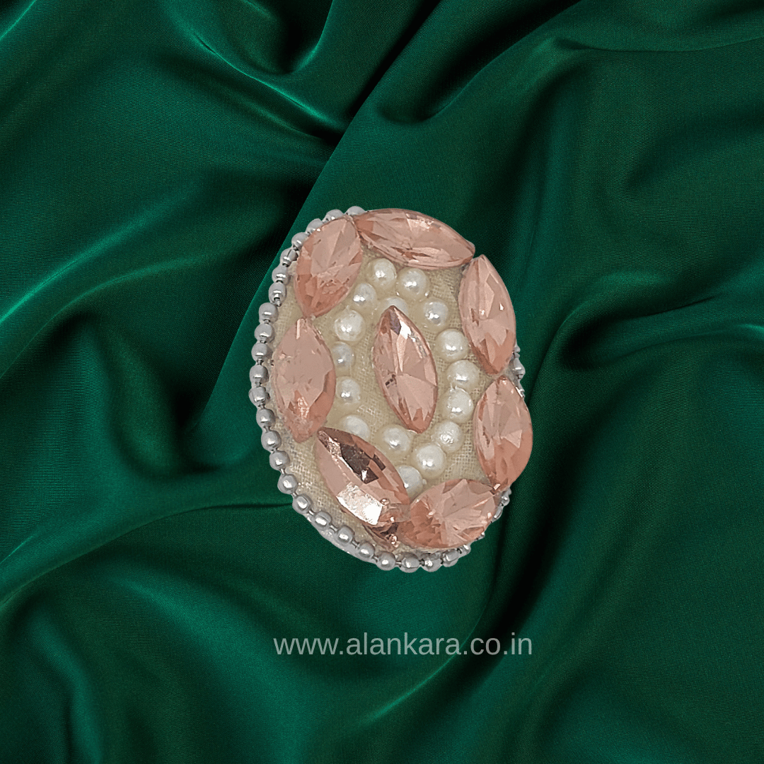 Peach Crystal Pearl Saree Pin featuring sparkling crystals and pearls on a green silk background.