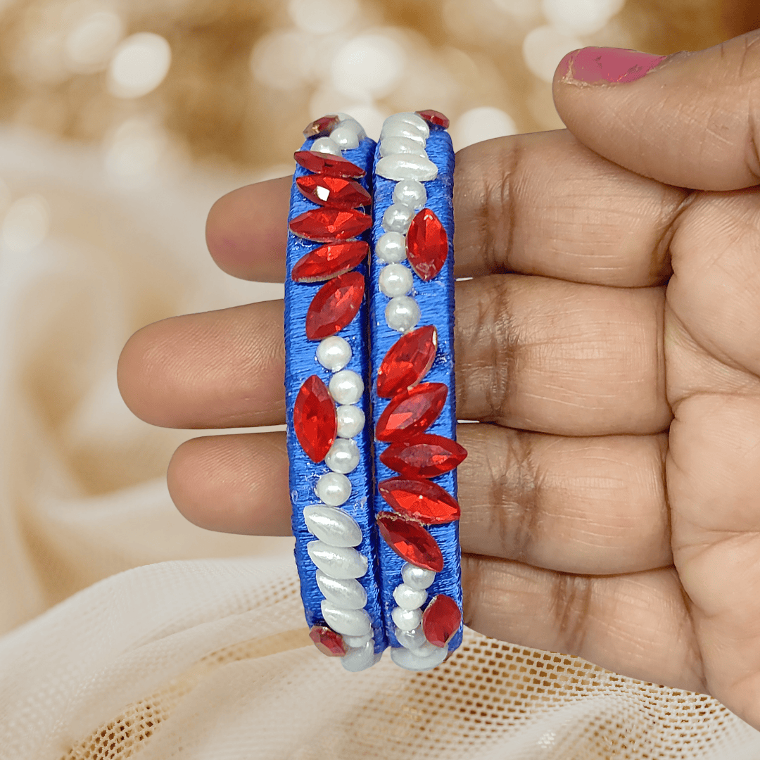 Royal blue floral pearl crystal silk thread bangles in hand, featuring red crystals and white pearls.