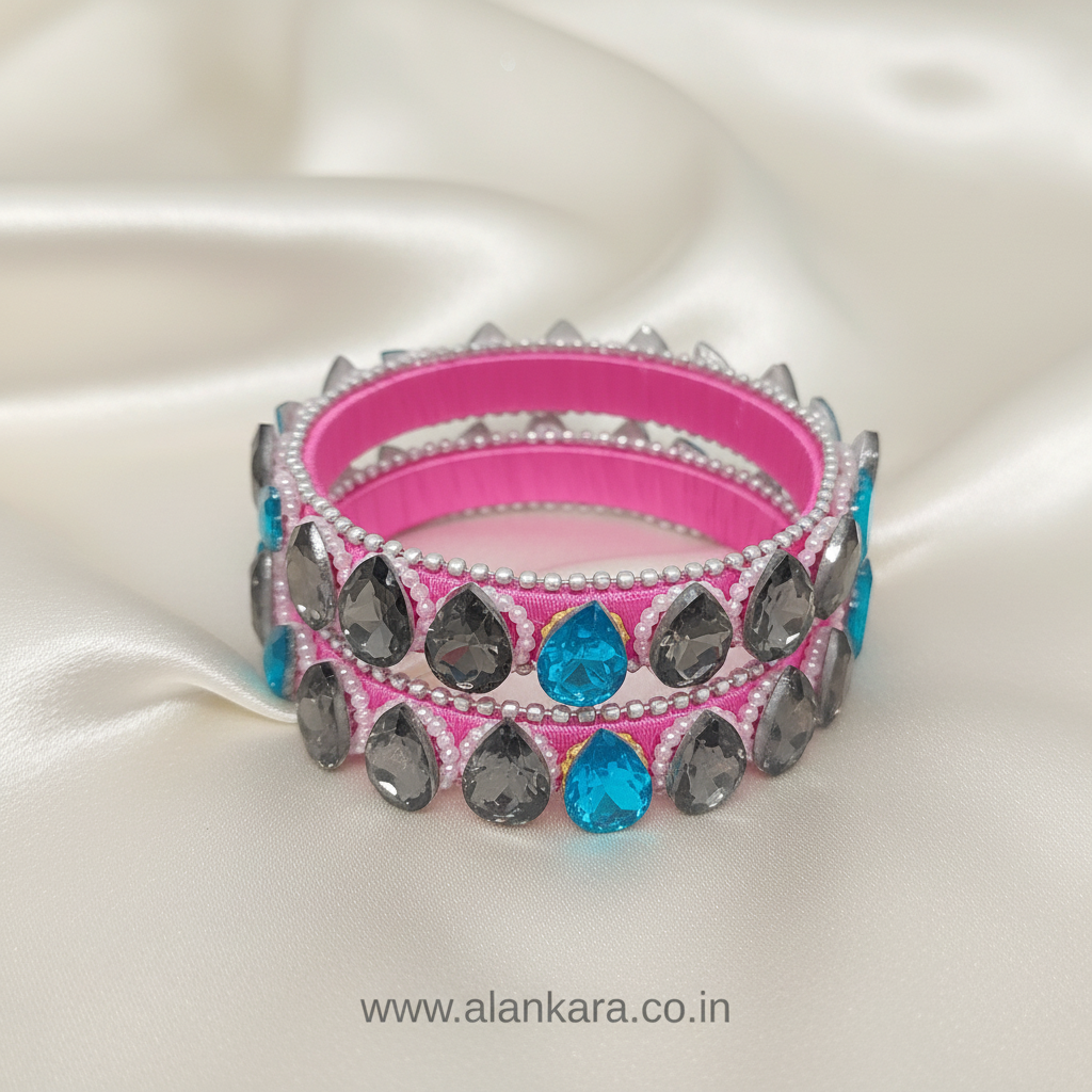 Pink Crystal Silk Thread Kada Bangles with grey and blue crystals, pearls, and silver beads against a satin background.
