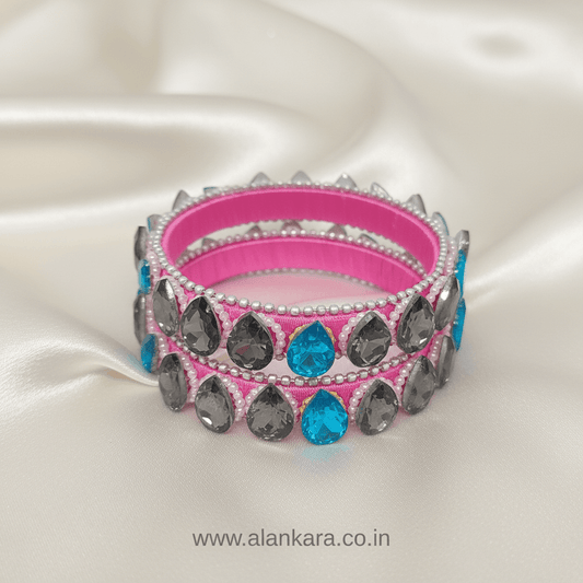 Pink Crystal Silk Thread Kada Bangles with grey and blue crystals, pearls, and silver beads against a satin background.