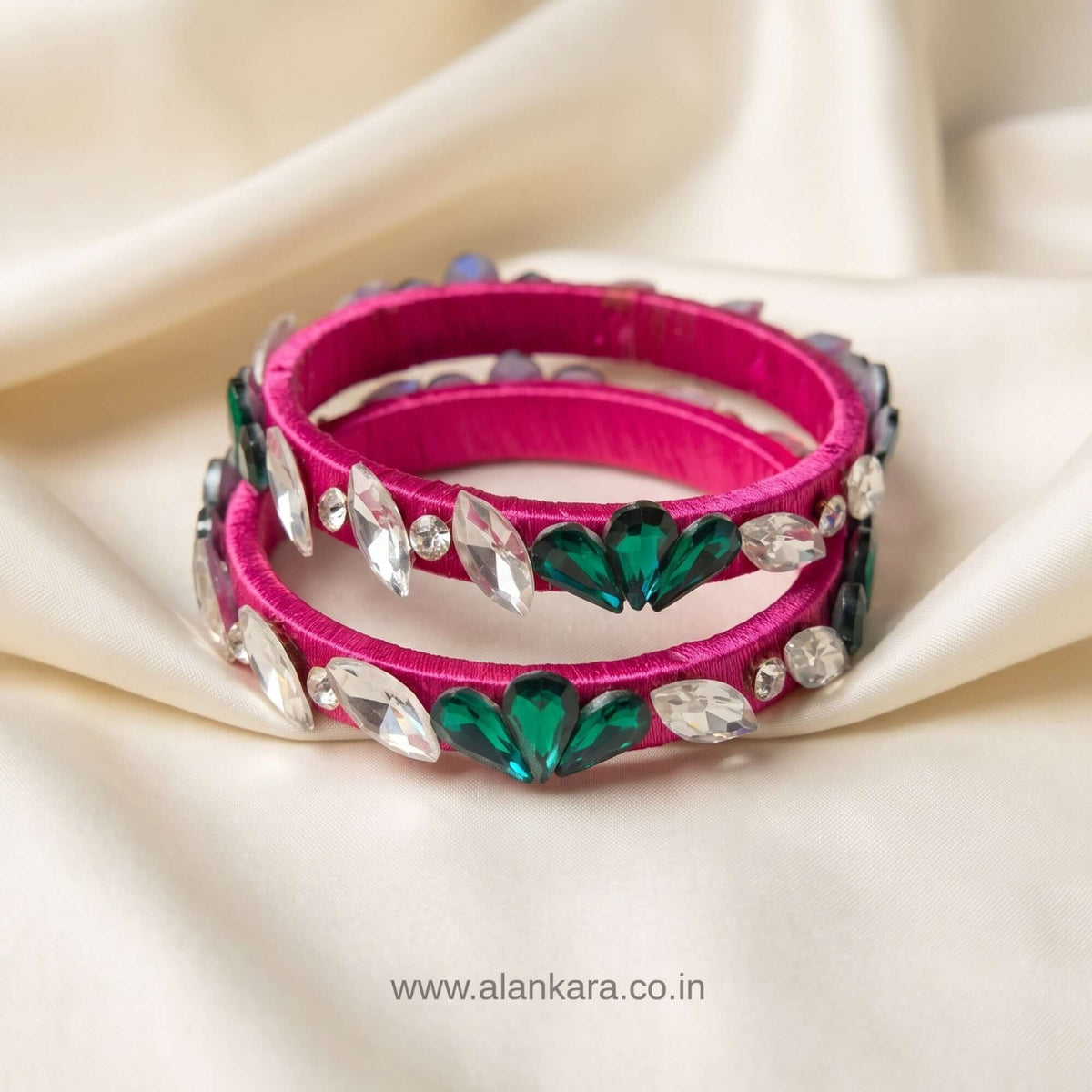 Rani pink floral crystal silk thread bangles featuring green and white crystals on a silky background.