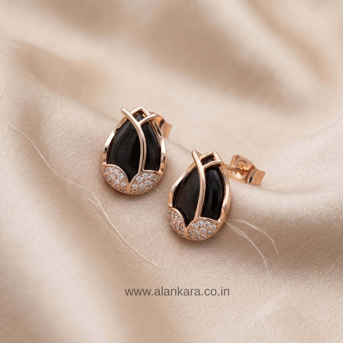 Black Leaf Stud earrings featuring black cubic zirconium on cream satin fabric.