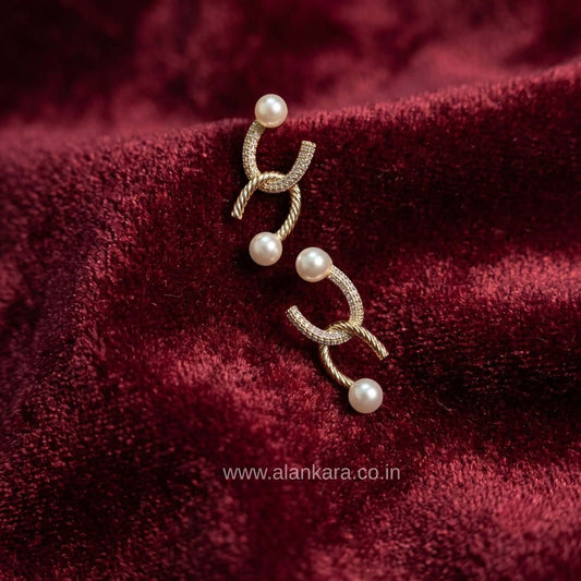 Golden Curve Pearl Stud earring showcasing a gold-plated design with cubic zirconia and pearl details on a rich maroon fabric.