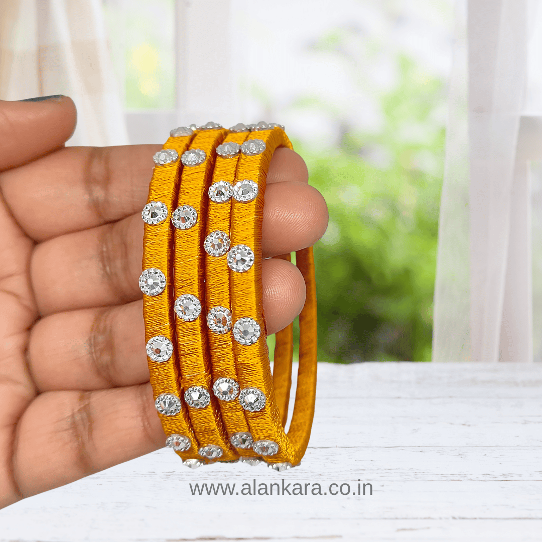 Golden Noori Silk Thread Bangles displayed in hand, showcasing rich golden-mustard silk thread and dazzling embellishments.