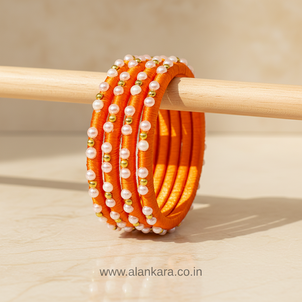 Orange Pearl Silk Thread Bangles featuring vibrant orange silk, white pearls, and golden beads on a smooth finish.