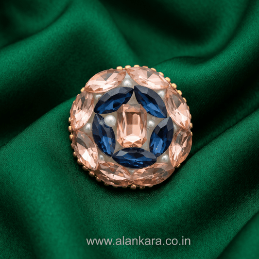 Peach & Blue Crystal Pearl Saree Pin on green fabric background, featuring intricate design and sparkling gemstones.