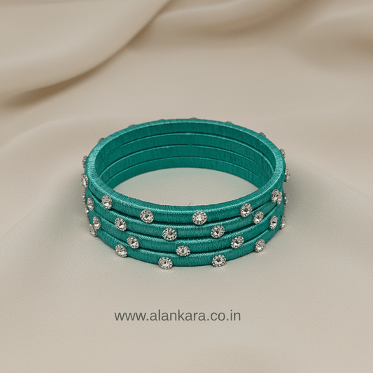 Pista Green Noori Silk Thread Bangles with silver detailing on a soft fabric background.