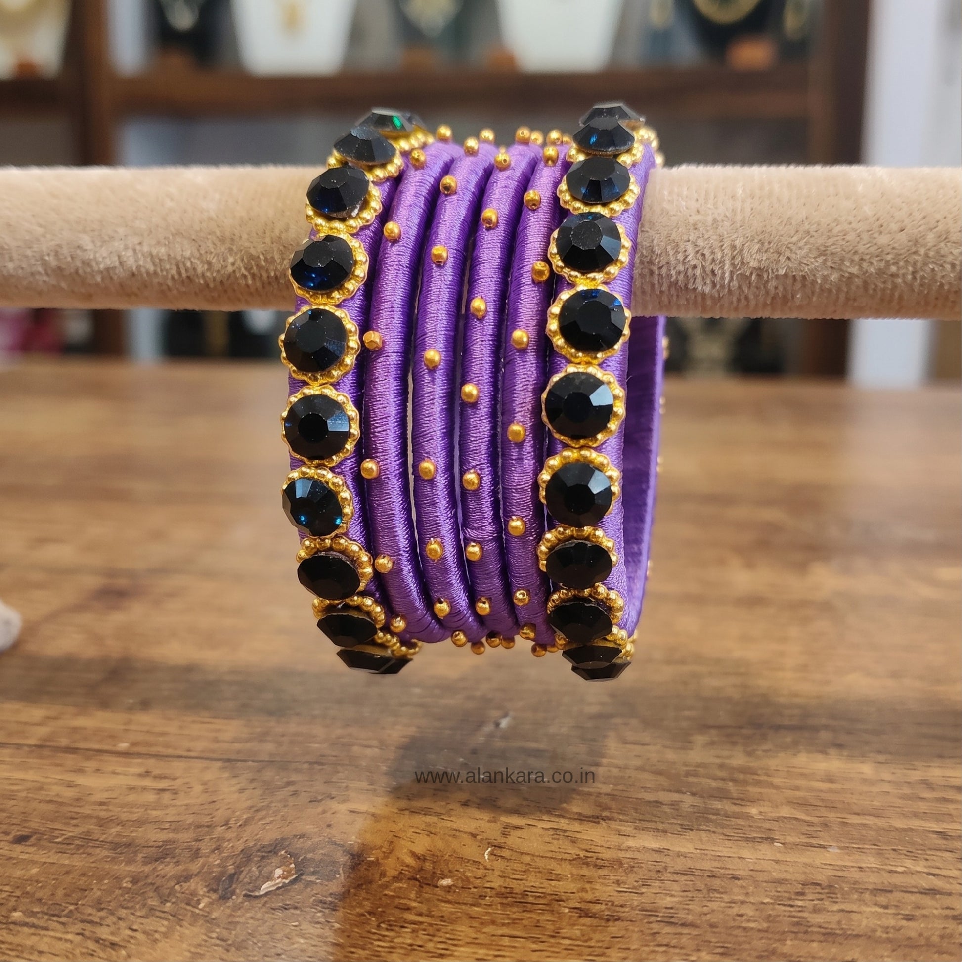 Royal Purple crystal Silk thread bangles with dark blue crystals and golden beads on a display.