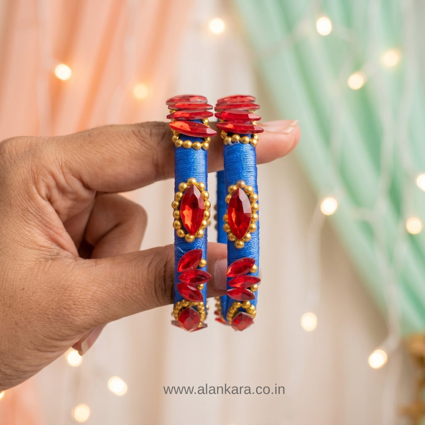 Royal Blue Red Crystal Silk Thread Kada Bangles held in hand with vibrant blue silk and shiny red crystals.
