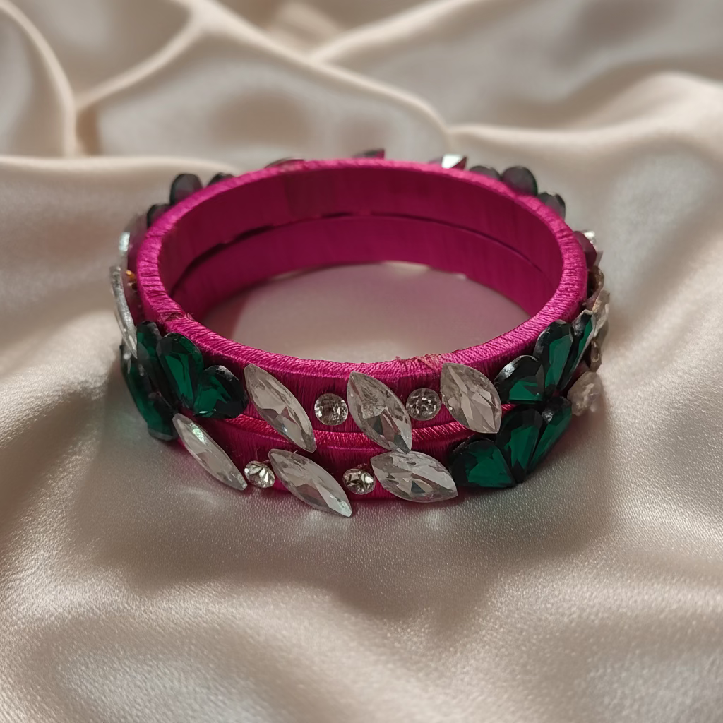 Rani Pink floral crystal silk thread bangles with decorative green and white crystals on a soft ivory fabric