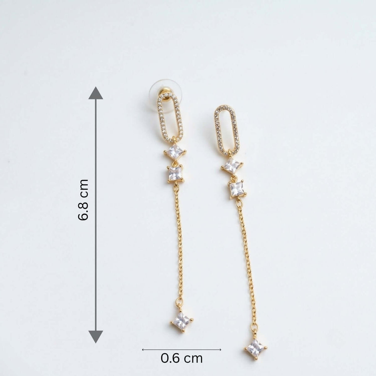 White Capsule Dangler earring featuring Cubic Zirconia stones, gold plating, and elegant design dimensions of 6.8 cm by 0.6 cm.