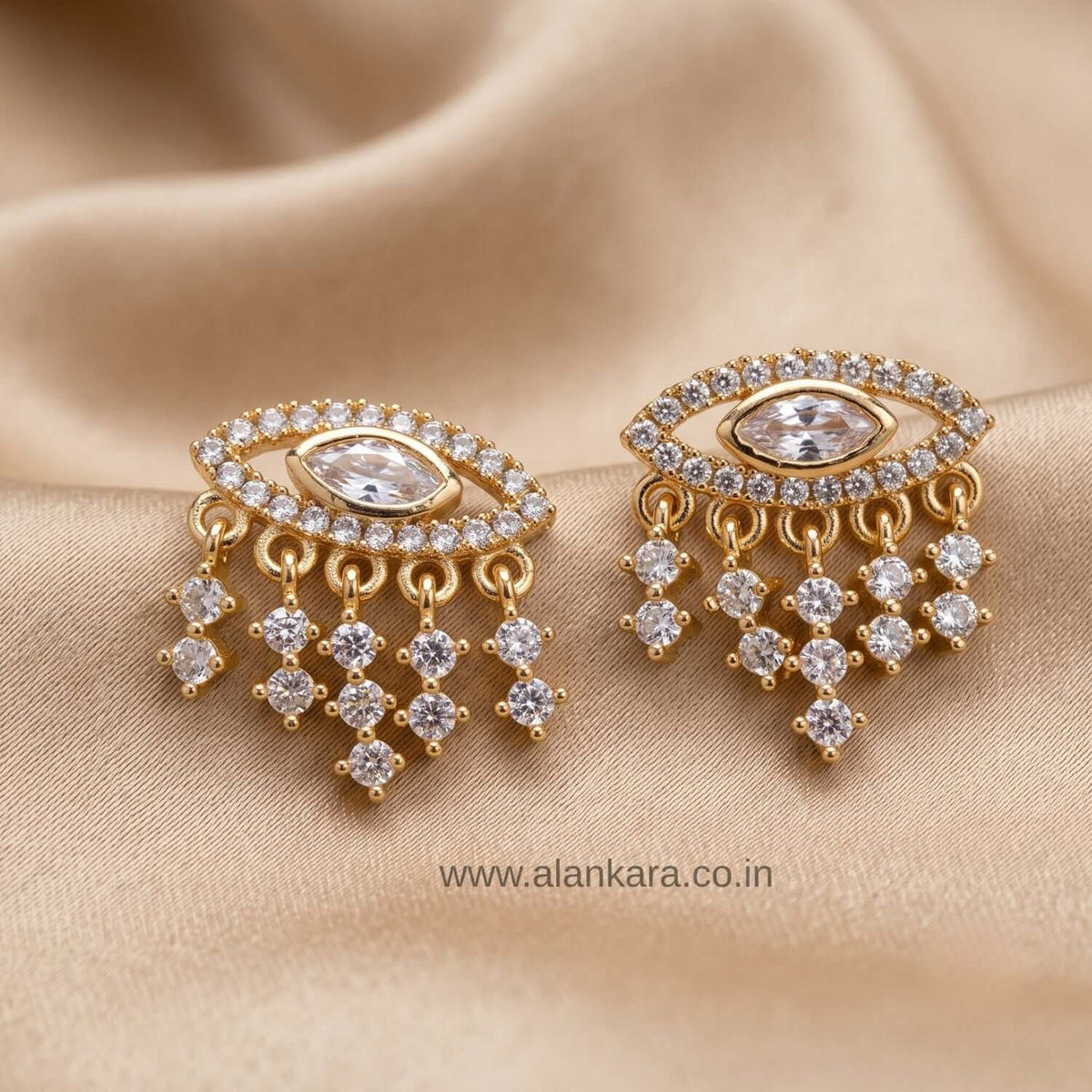 White Evil Eye Stud earrings featuring gold plating and sparkling cubic zirconia stones on a silk background.