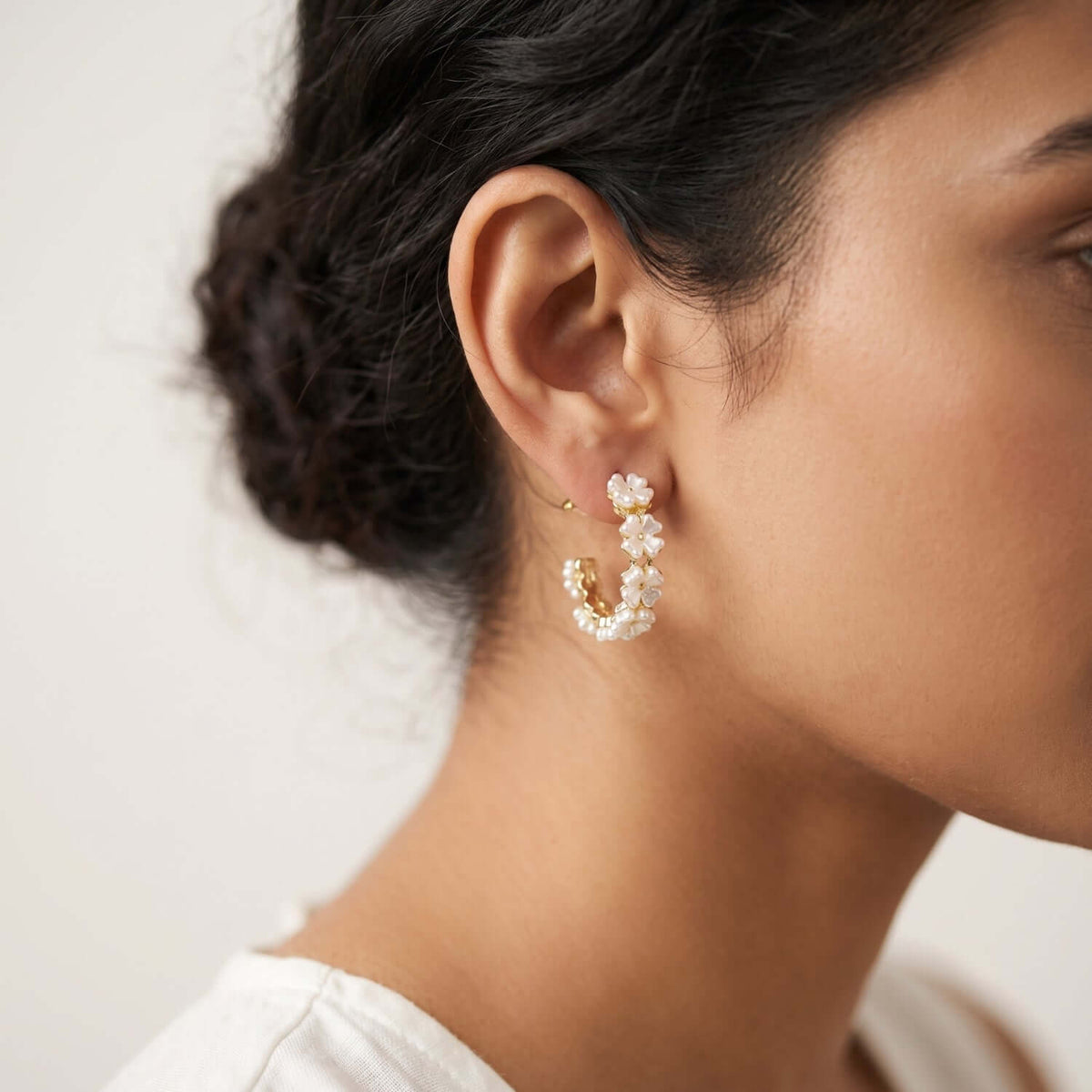 Close-up of a woman wearing White Golden Pearl Hoop earrings, showcasing elegance with intricate pearl details.