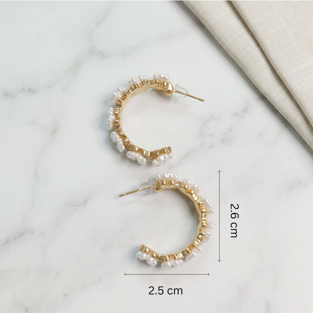 White Golden Pearl Hoop earrings displayed with dimensions on a marble surface, showcasing stylish pearl accents.