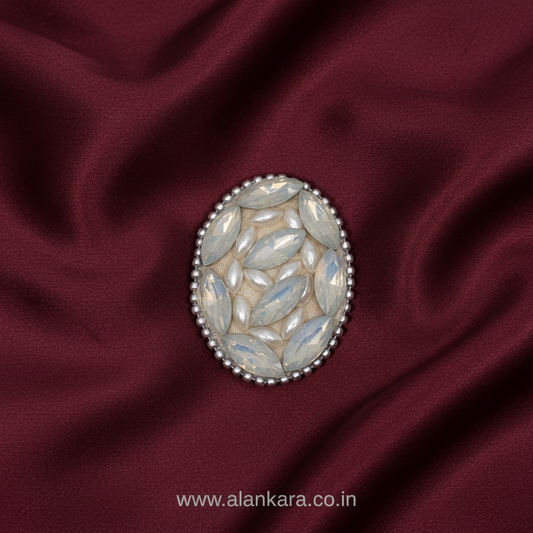 White Pearl Crystal Saree Pin resting on rich burgundy fabric, showcasing elegant design and intricate details.