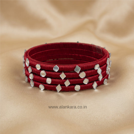 White Maroon Silk Thread Bangles with silver-white mirror embellishments on a beige background.