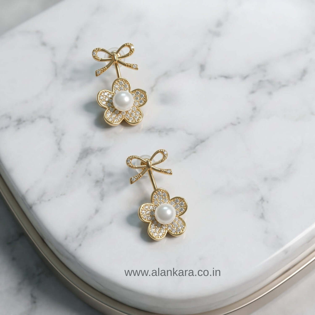 White Pearl Bow Stud earrings featuring a floral design with cubic zirconia and a pearl center on a marble surface.