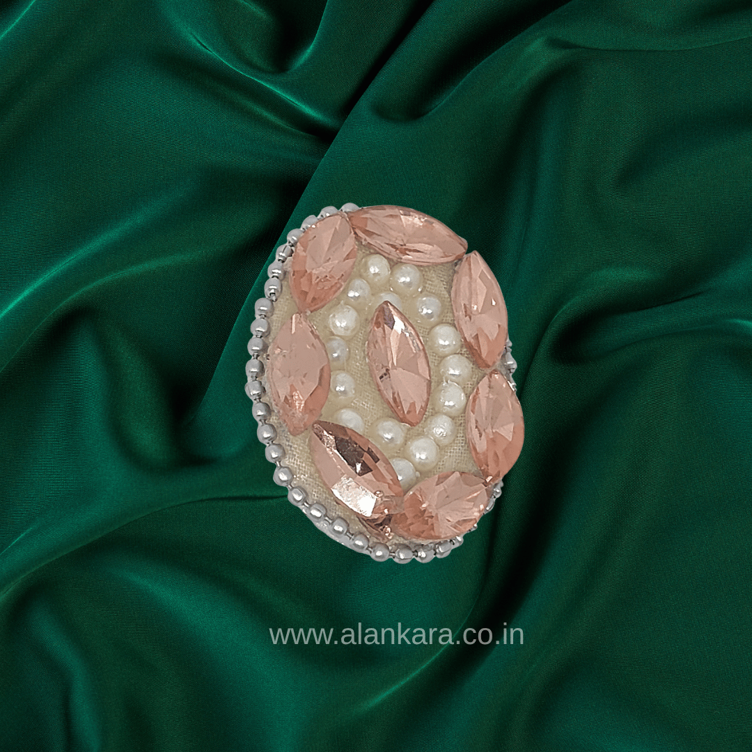 Peach Crystal Pearl Saree Pin featuring sparkling crystals and pearls on a green silk background.