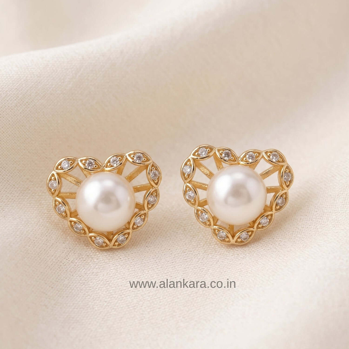 Stylish Pearl heart stud earrings with cubic zirconia accents on a soft fabric background.